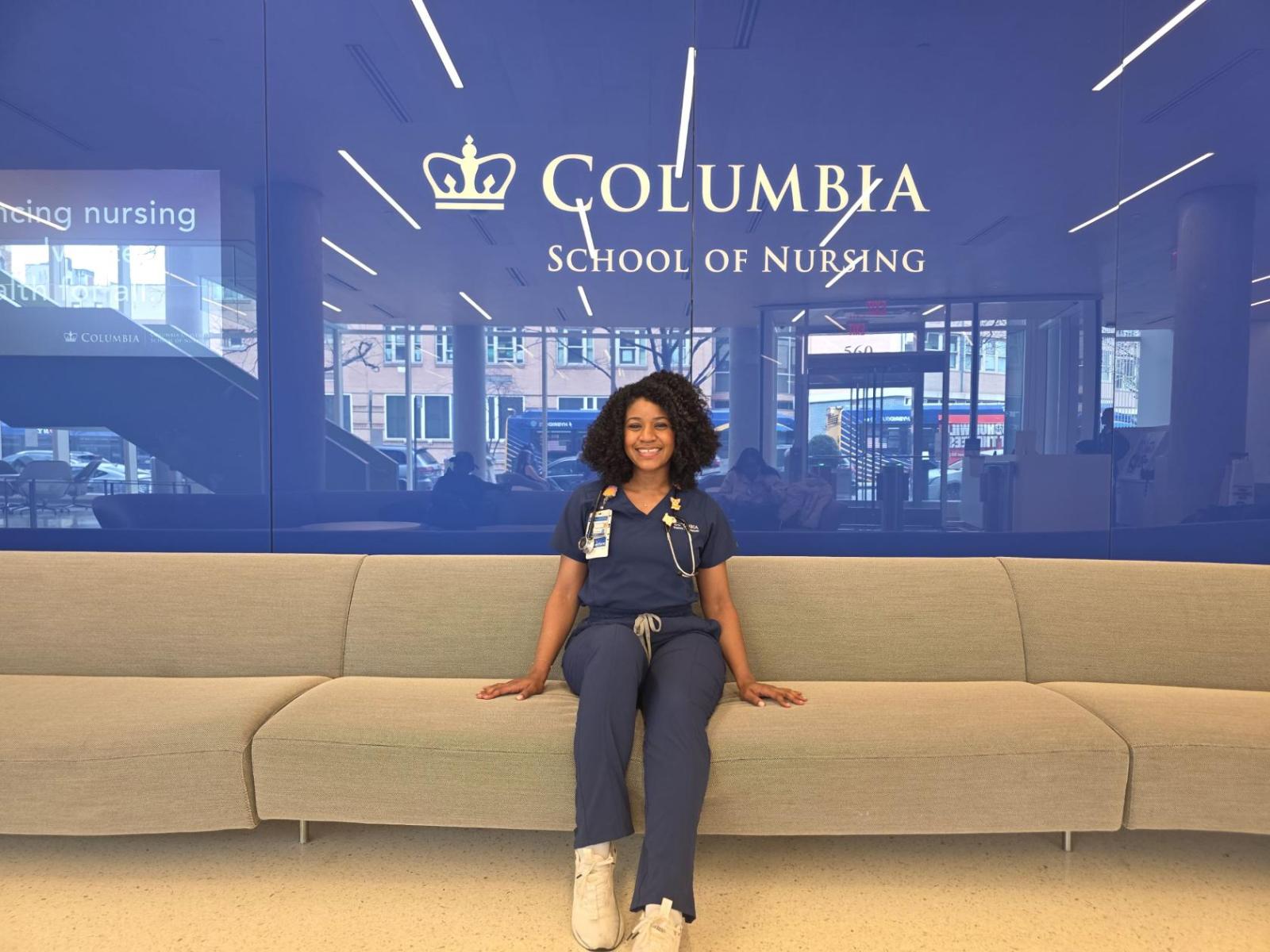 Columbia Nursing student sitting in front of blue wall