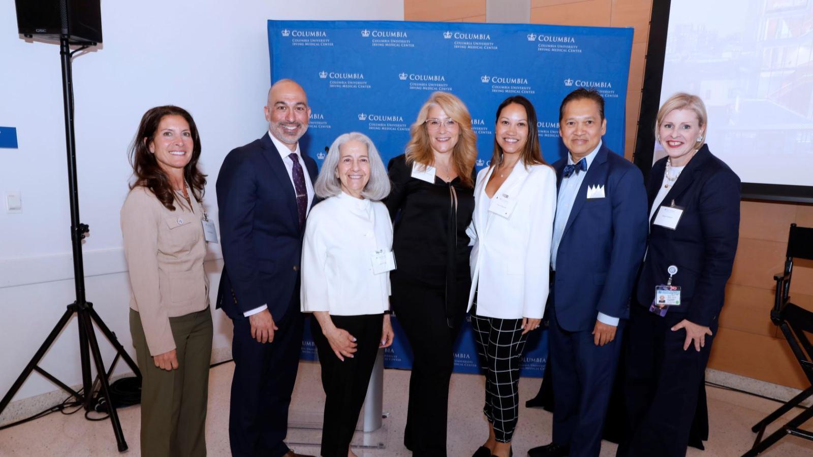 7 individuals posing for group photo in front of stage