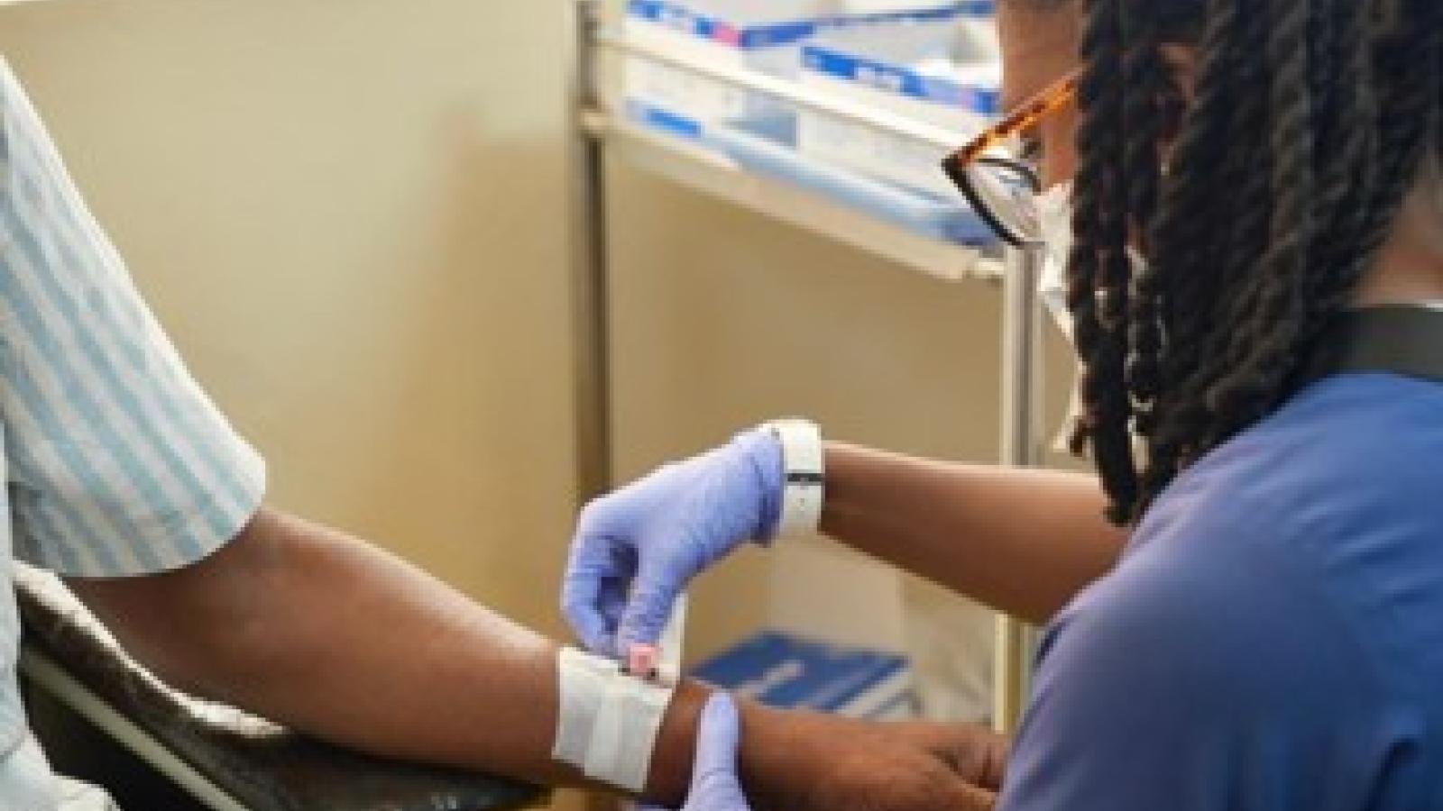 Global fellow bandaging an arm for a patient in Zambia