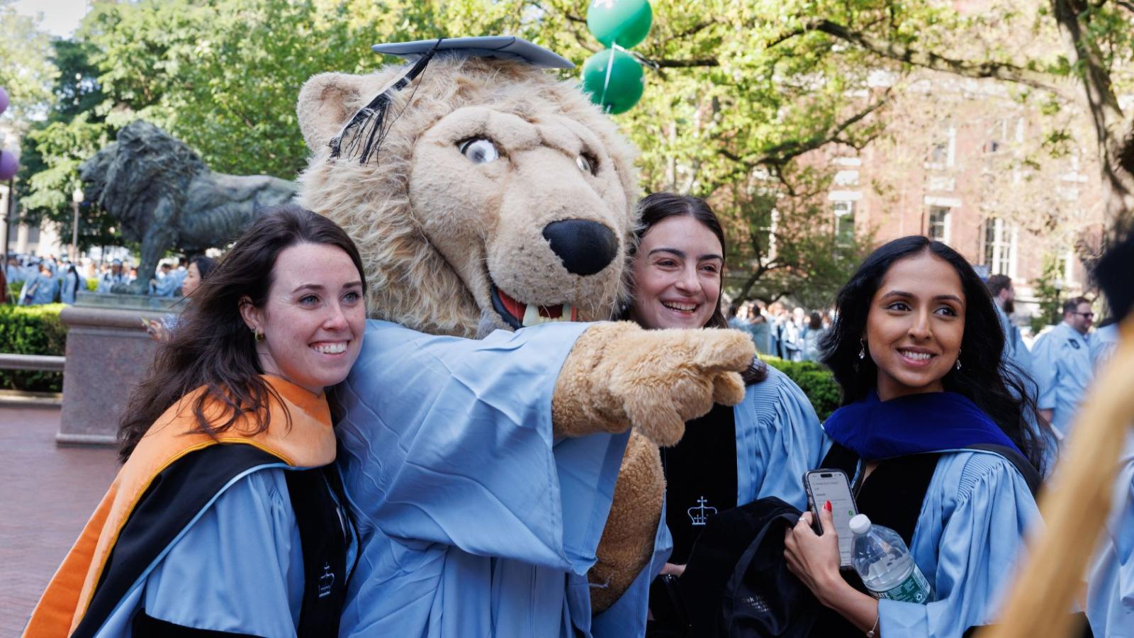 Graduates posing with Columbia Lion mascot at commencement