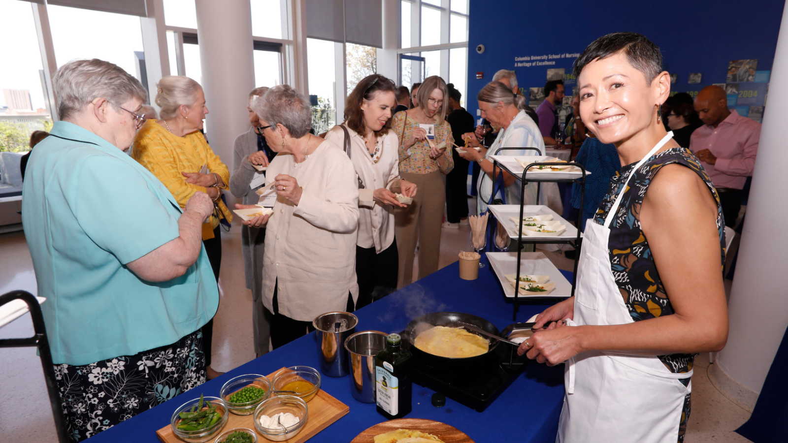 Person doing cooking demonstration as onlookers taste samples