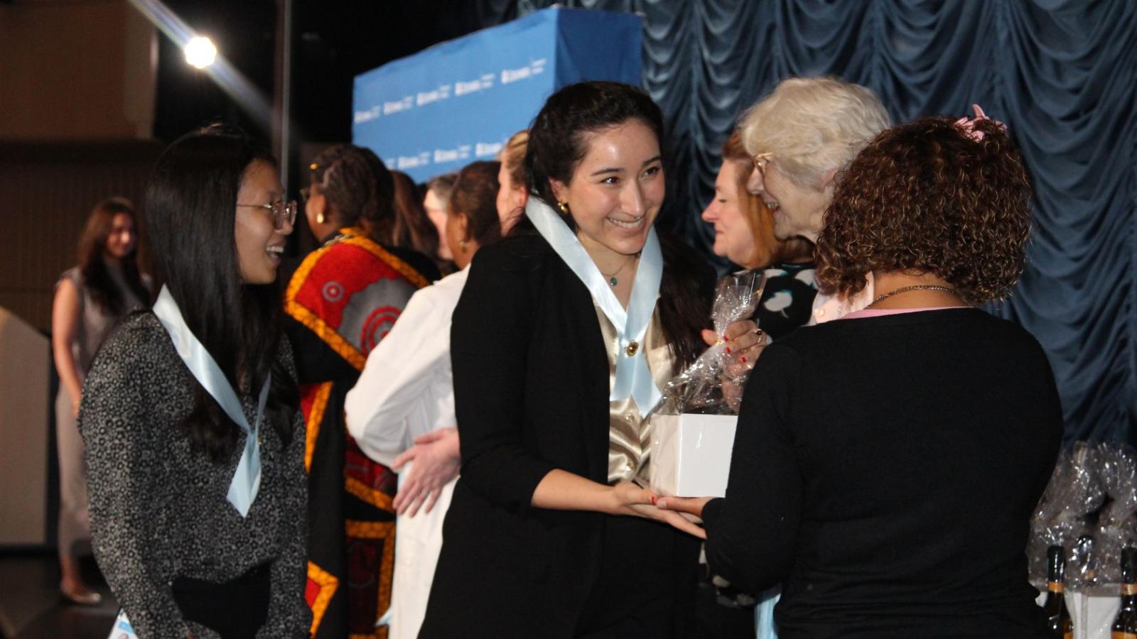 Nursing graduates receiving gifts on stage during ceremony