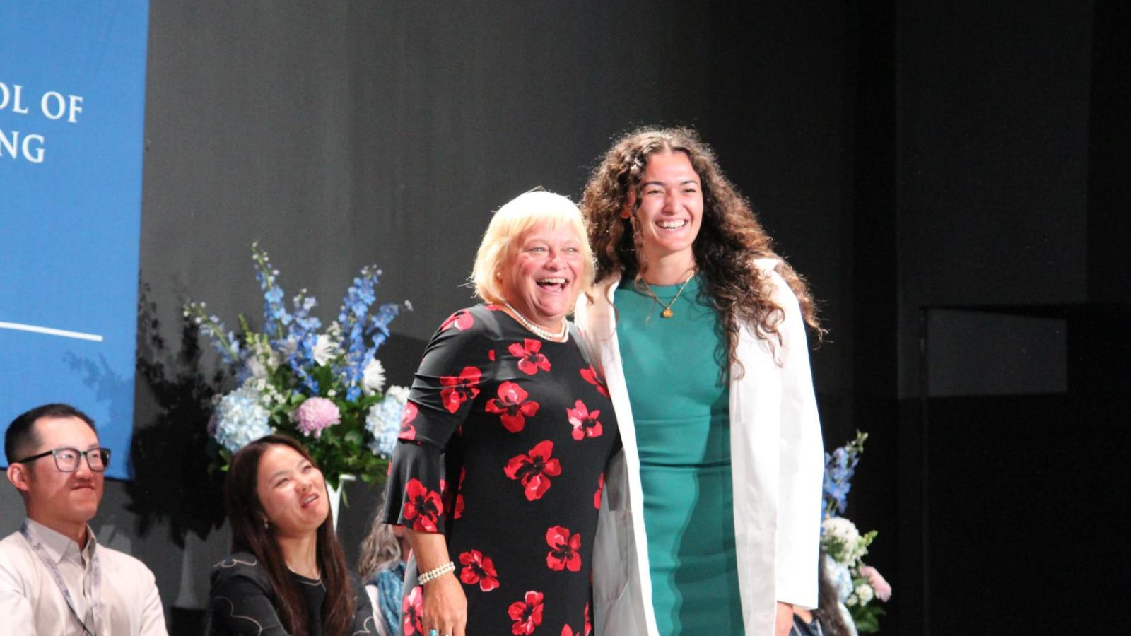 Student posing with faculty after receive their white coat at White Coat Ceremony 2024.