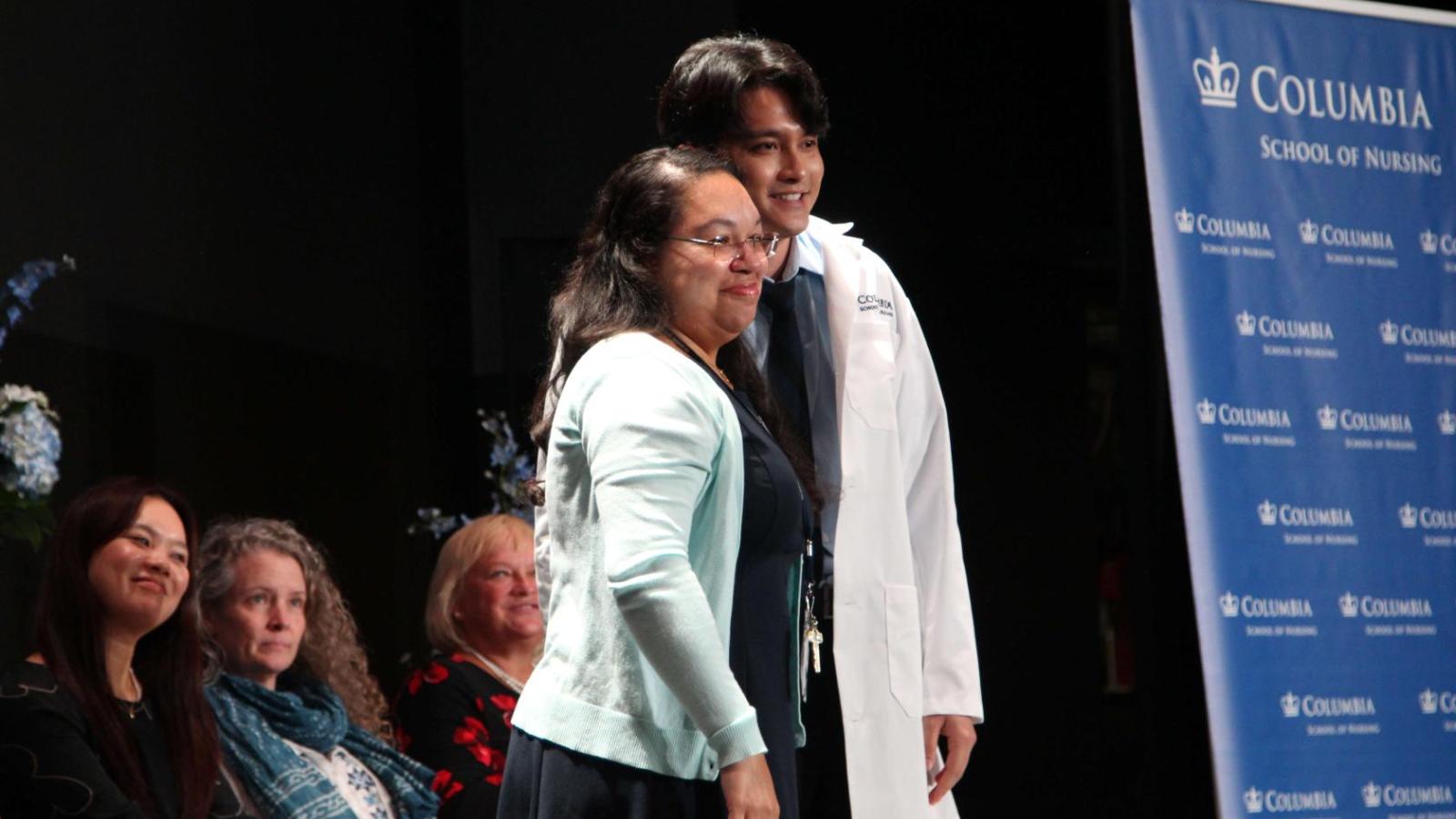 Student posing with faculty after receive their white coat at White Coat Ceremony 2024.