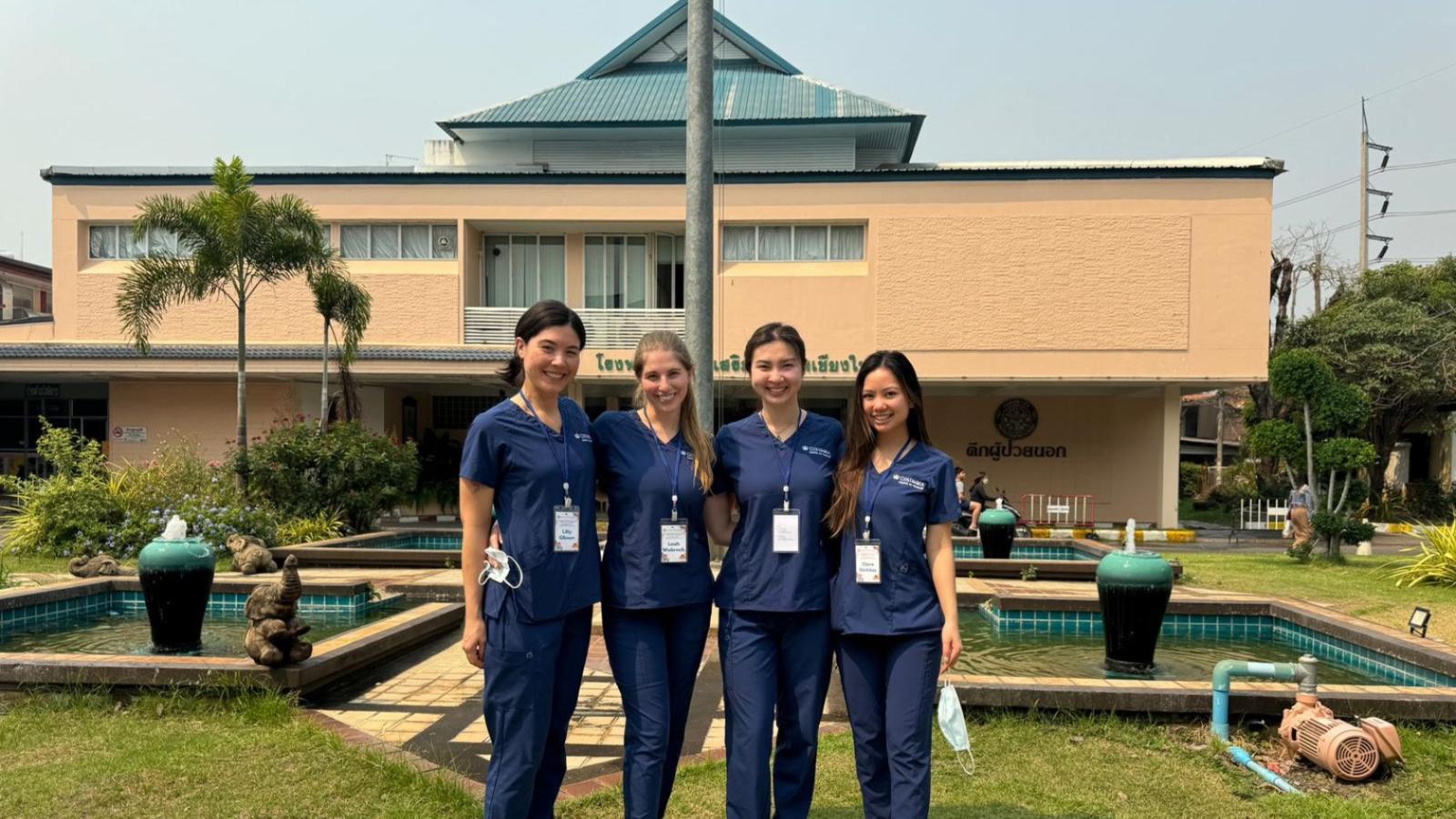 Four Columbia Nursing students standing outside rural building