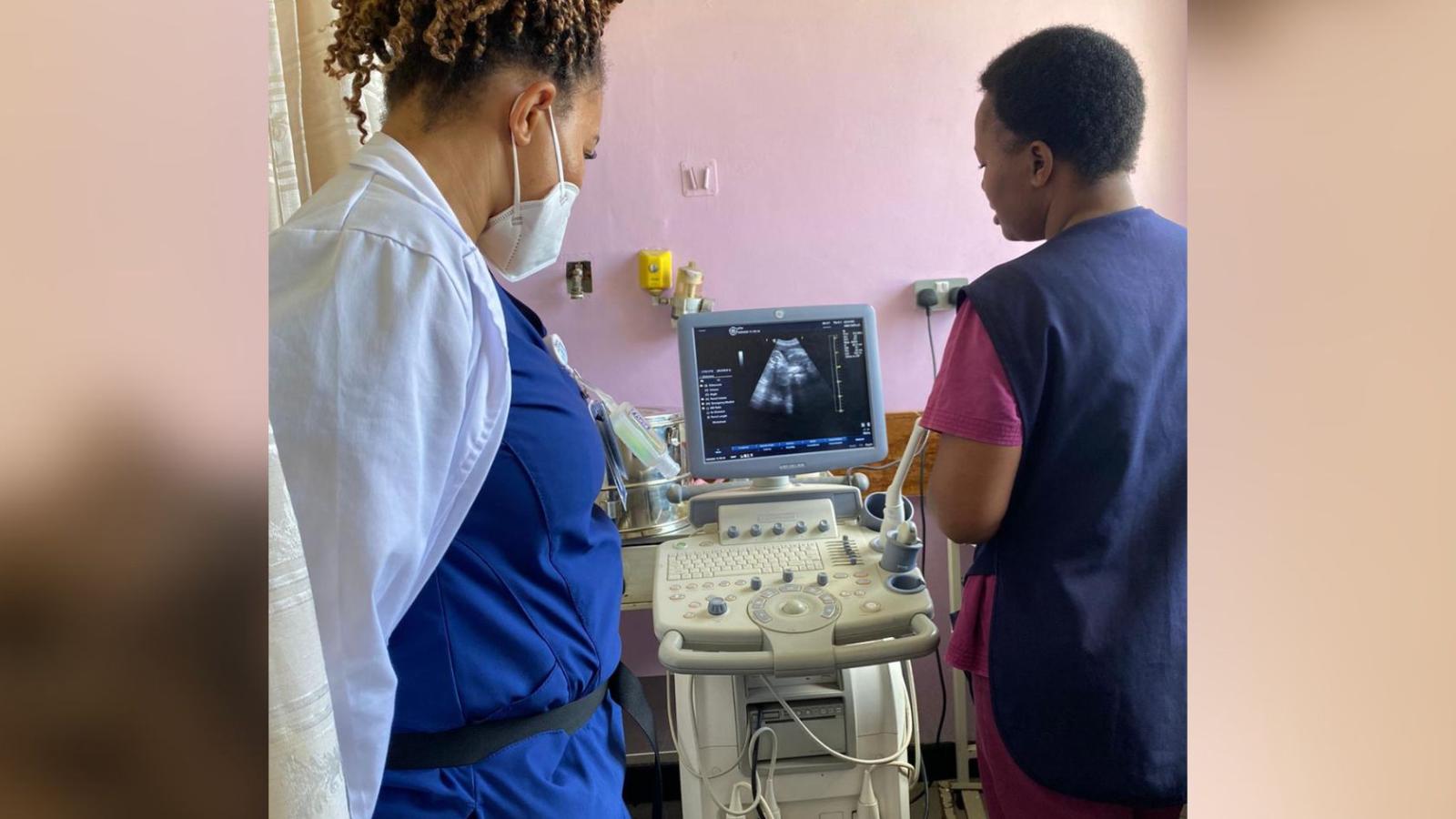 Two healthcare providers looking at ultrasound image on monitor
