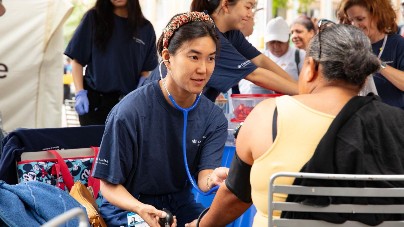 Clinician from the Nurse Practitioner Group taking blood pressure of member from the community