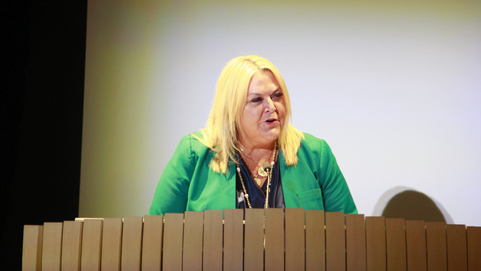 Female speaker with green jacket at podium
