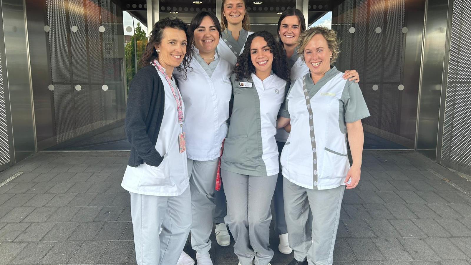 student in front of hospital with colleagues.