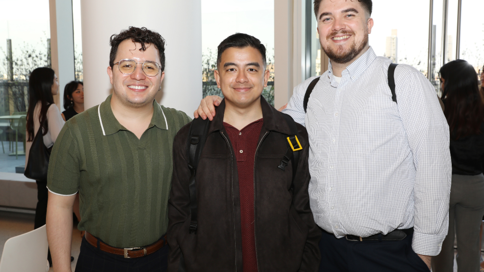 Three men smile together side by side