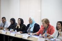Five women and one man sitting at a long table in a meeting.
