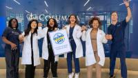 Nursing students jumping and holding a sign about Columbia Giving Day on October 28, 2026