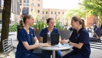 Three Columbia Nursing students studying at a table outside.