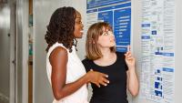 Two PhD students looking at a research poster together.