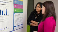 Two researchers looking at a research poster.