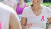 woman smiles while running charity race to benefit breast cancer research