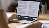 Research paper being viewed on a laptop by an individual.