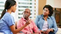 Nurse making notes during home visit with senior couple