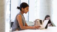 Columbia Nursing Student works on coursework using laptop in atrium of School of Nursing.