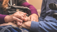 Provider holding hands with elderly patient
