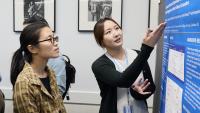Columbia Nursing PhD candidate explains their research project to faculty during presentations of research posters.
