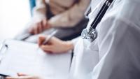 A nurse practitioner's stethoscope with a patient in the backdrop