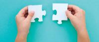 Hands holding two puzzle pieces