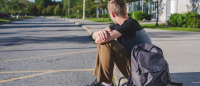 Lonely student sitting on school curb