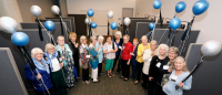 Group of alumni standing in semi-circle holding blue and white balloons