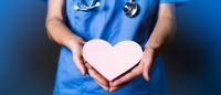 Nurse in blue scrubs holding a pink heart