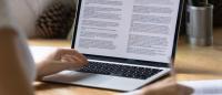Research paper being viewed on a laptop by an individual.