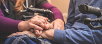 Provider holding hands with elderly patient