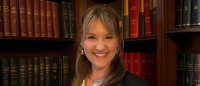 Headshot of Columbia Nursing PhD graduate, Sophie Junak, against a wall of books