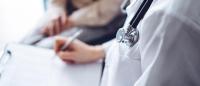 A nurse practitioner's stethoscope with a patient in the backdrop